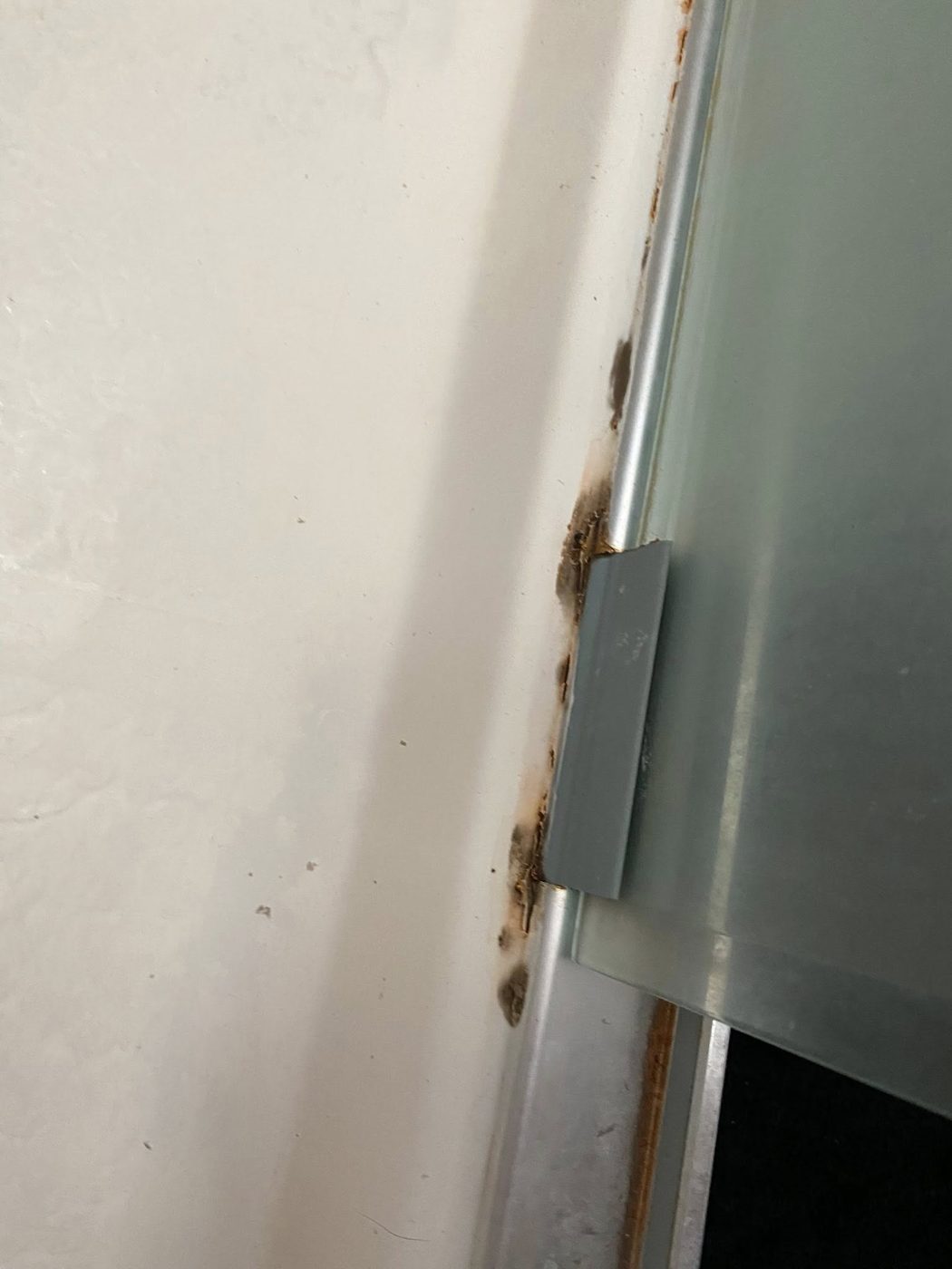 Rusted shower door track before fix